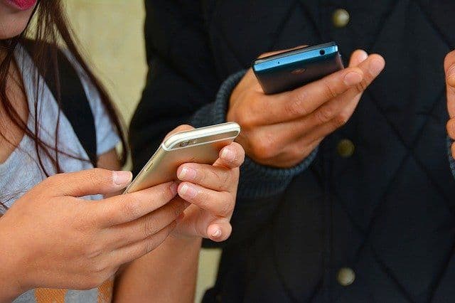 A man and a woman look at their phones