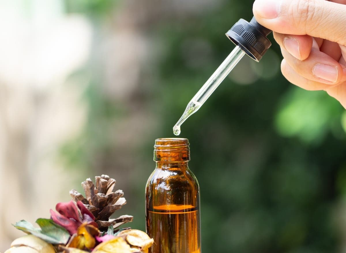 Hand dropping flower remedy into brown bottl
