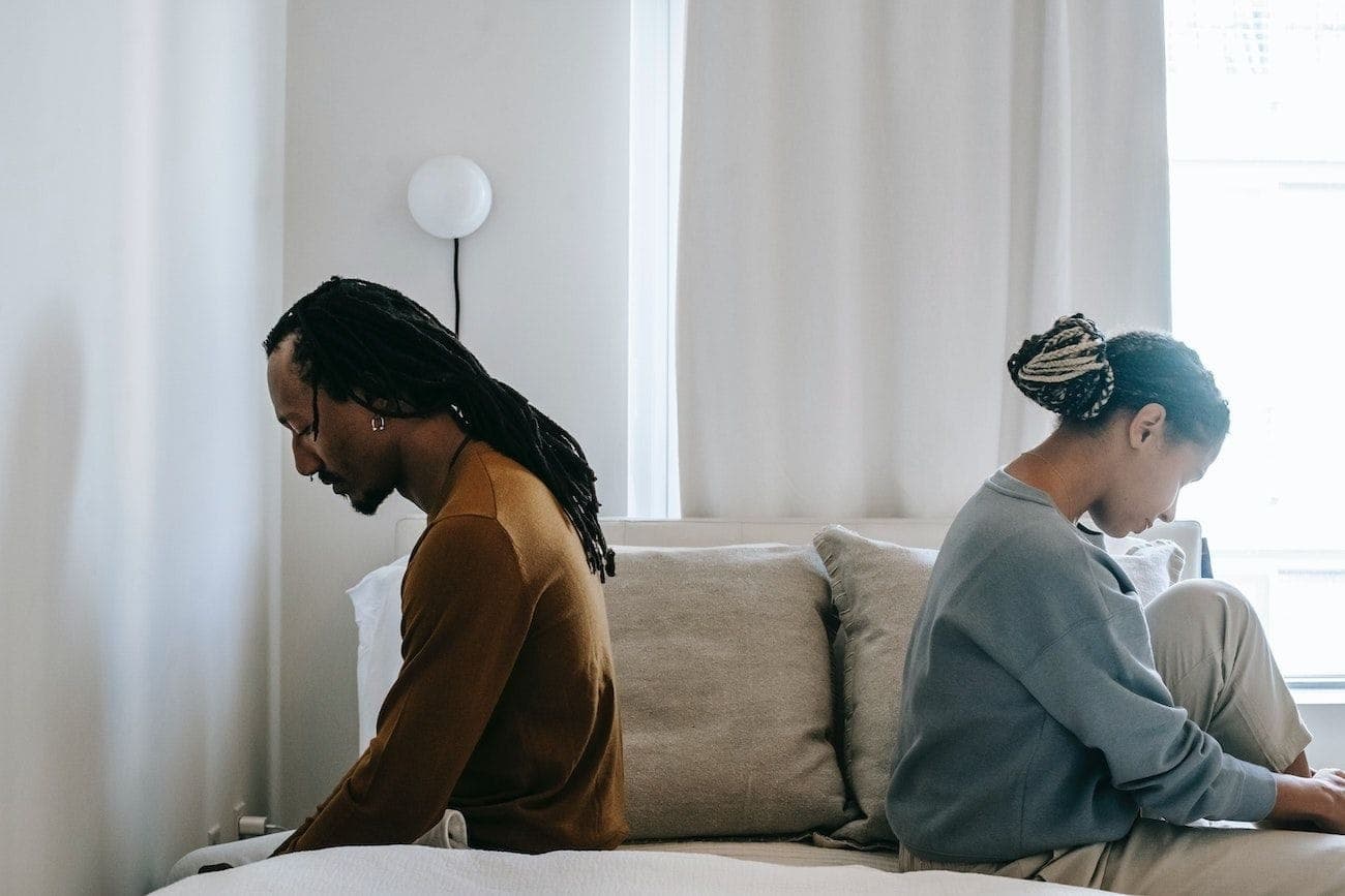 Unhappy couple sitting apart on bed